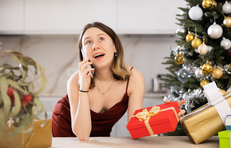 Attractive woman is preparing presents and discussing it with someone on a mobile phoneの写真素材