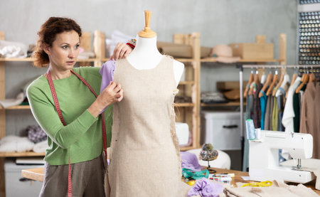 Fashion designer fitting dress on mannequin in dressmaker studioの写真素材