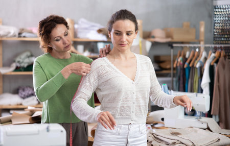 Female fashion designer measuring client for tailored clothingの写真素材