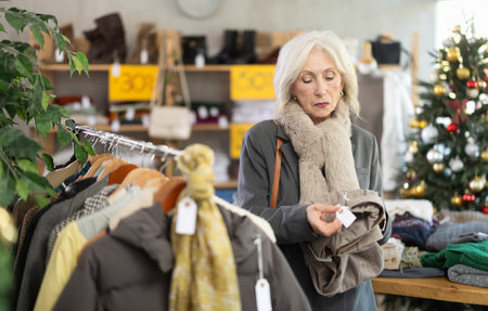 Mature woman chooses fashionable trousers for winter season in storeの写真素材