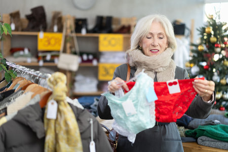 Mature female shopper selects panties in fashionable clothing boutiqueの写真素材