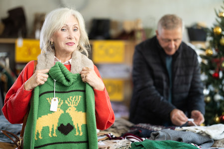 Elderly woman choosing a reindeer sweaterの写真素材
