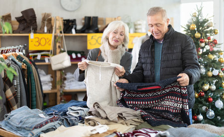 Elderly married couple choose sweater for the winter season together in fashionable clothing store.の写真素材
