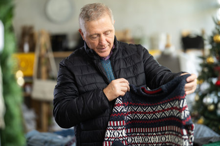 Mature male shopper selects sweater in fashionable clothing boutiqueの写真素材