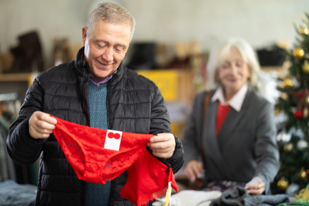 Mature male shopper selects red lingerie as a Christmas gift in fashionable clothing boutiqueの写真素材