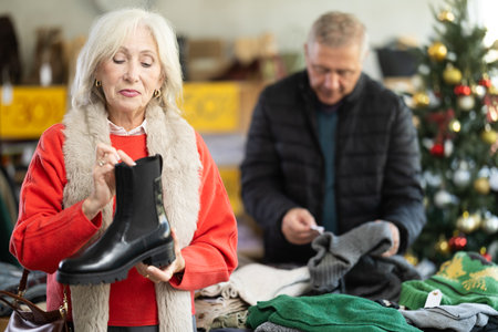 Happy elderly woman chooses fashionable platform boots in shoe storeの写真素材
