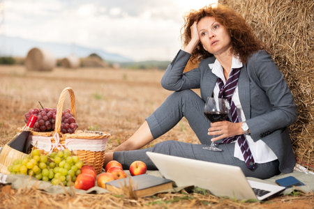 Woman in business suit spends time in field, settles down in nature with laptop.の写真素材