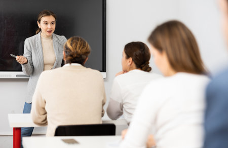 Young female tutor teaching students in college classroomの写真素材