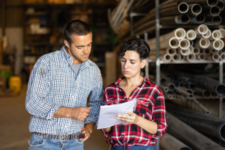 Man and woman verifying check list in warehouseの写真素材