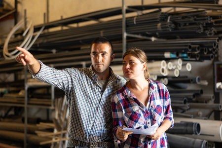 Man and woman verifying check list in warehouseの写真素材