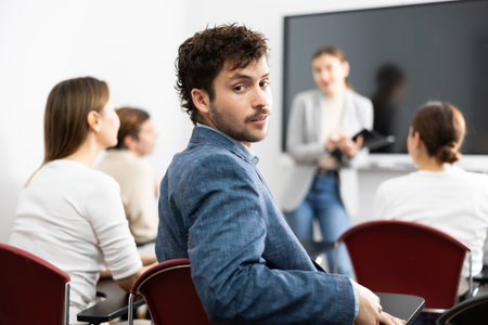 Portrait of successful young man participating in language courses with group of people in classroomの写真素材