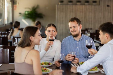 Couples of women and men eating and talking in restaurant