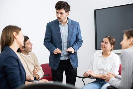 Young male tutor teaching students in college classroom