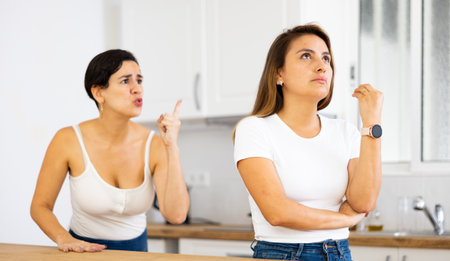Woman listening her girlfriend standing behind and quarreling with herの写真素材