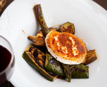 Tasty goat cheese with grilled eggplant and vegetables served on plateの写真素材