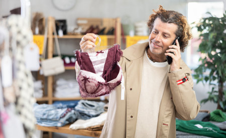 man chooses underwear and calls his wife on the phoneの写真素材