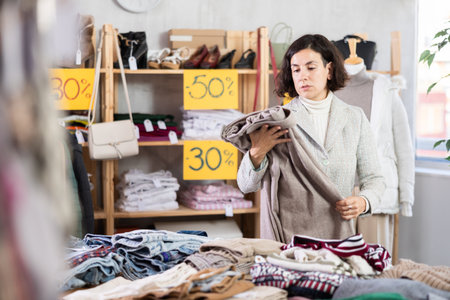 Focused woman client choosing pants or stylish trousers in clothing mallの写真素材