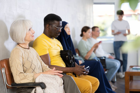 Elderly woman sitting on chair waiting in line at receptionの写真素材