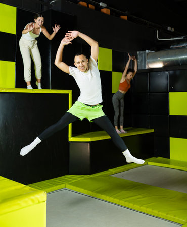 Fitness, fun, leisure and sport activity concept - happy man jumping on trampoline indoorsの写真素材
