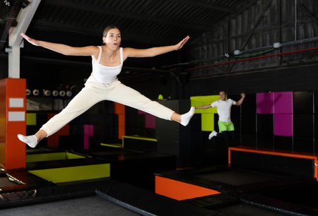 Cheerful young girl jumping in indoor trampoline arenaの写真素材