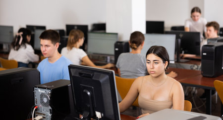 Interested teenage students during lesson in computer room of library. Focus on young girlの写真素材