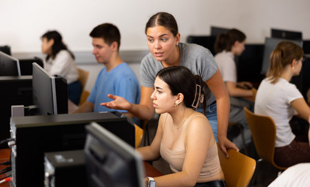 Teacher and teenage student studying in computer class