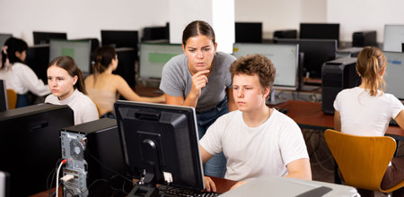 Woman teacher helps guy with learning on computer in school