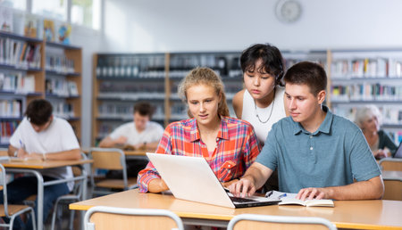 Schoolchildren help each other solve the task in school libraryの写真素材