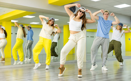Group of young teen boy and girls dancing in spacious hall with mirrors. The concept of sport, dance...