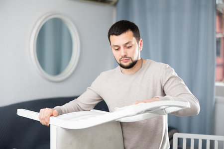 Smiling man wiping dust from a chair in roomの写真素材
