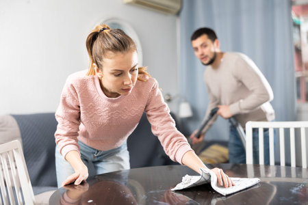 Young couple cleaning table in living room