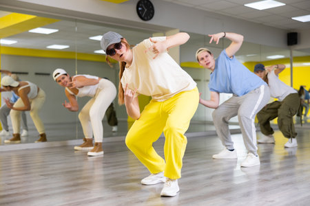 Group of teenagers having dance training in studio, performing contemporary hip hop elementsの写真素材