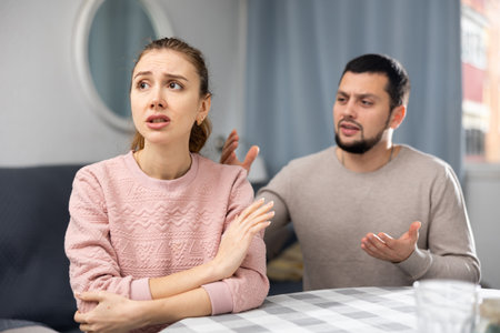 Upset woman gesturing enough to husband apologizing after quarrelの写真素材