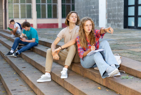 Girl points her finger to guy on the street during break in collegeの写真素材