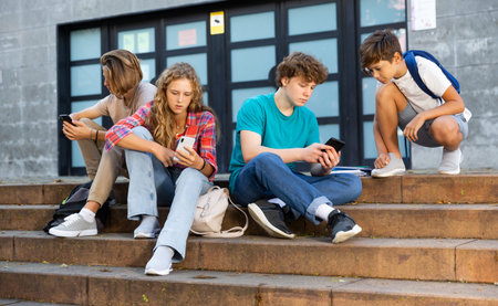 Schoolers using gadgets on break outside college