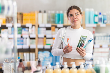 Woman choosing a set of dental products at the pharmacyの写真素材
