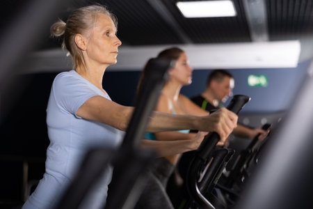 Mature woman exercising on an elliptical trainer in gymの写真素材