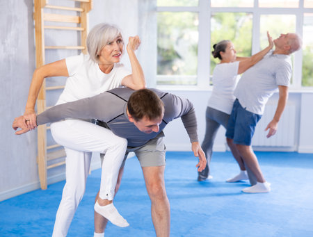 Senior woman in pair with middle-aged coach train Krav Maga and self-defense skills.の写真素材