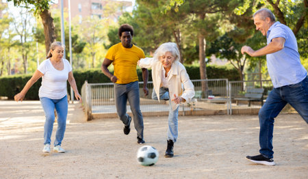 Cheerful group of mixed-race middle-aged and older adult people playing football game outdoorsの写真素材