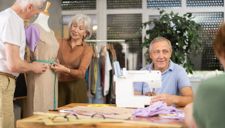 Smiling senior man stitching at machine during group classの写真素材