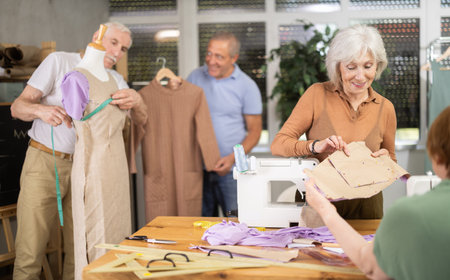 Elderly man and woman working with mannequin and making pattern in classの写真素材