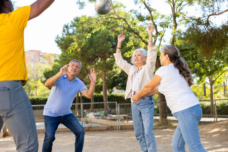 Old multinational people playing volleyball activity on a summer playground for sports in spring outsideの写真素材