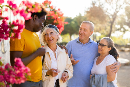 A group of friendly multiracial mixed-sex mature adult people standing outside talking to each other