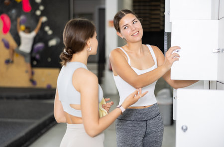 Two young women talking in locker roomの写真素材