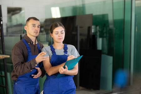 Glass workshop workers discussing inventory results with clipboard