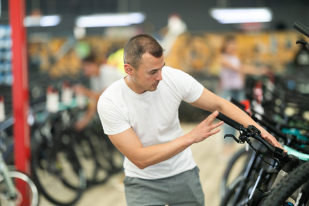 Interested man examining bike handlebar system in storeの写真素材