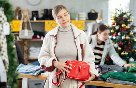 Woman client looks at products in store, choose closely ladys bagの写真素材