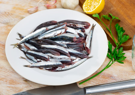 Pile of small raw fish is piled on plate, ready for frying.の写真素材