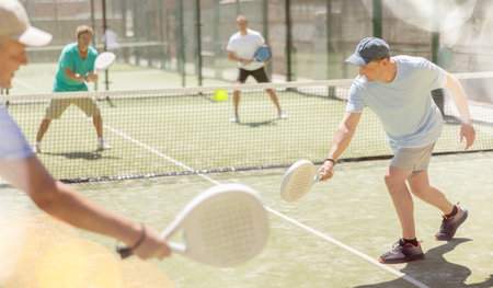 Men play padel on an outdoor tennis court. Hitting the ball with racketの写真素材