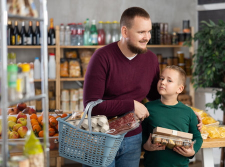 Young man with son choosing groceries in storeの写真素材